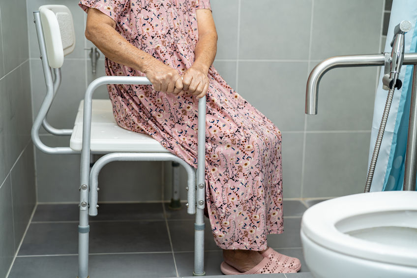 senior woman using shower seat and grab bar in shower