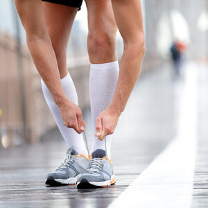 fitness model wearing compression socks while ting his running shoes