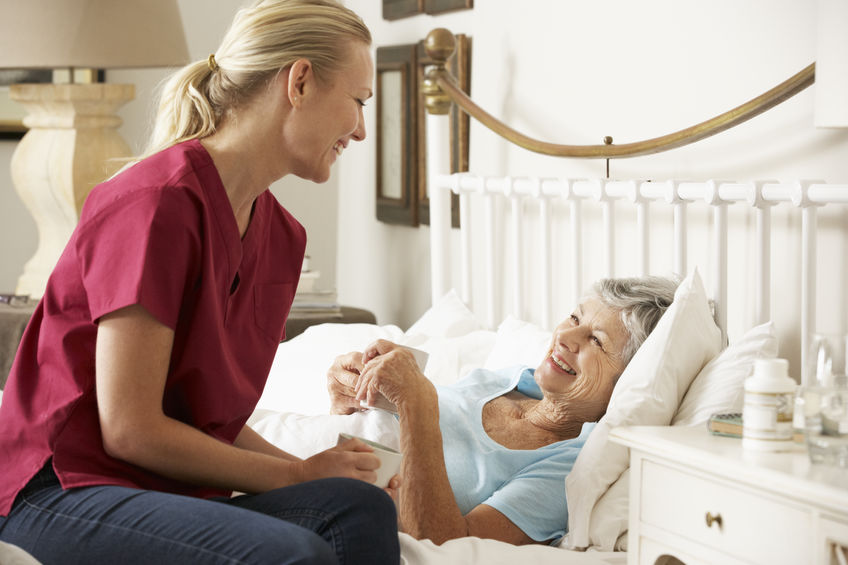 Homecare worker checking in on elderly patient in bed