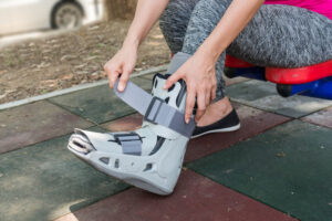 Women strapping her foot into an orthotic walking boot after injuring her leg.