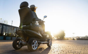 Woman riding a four-wheel mobility electric scooter on a city street.