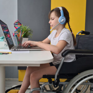 girl in wheelchair on video conference at home. Remote learning and communication with friends
