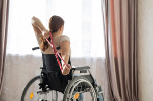 Caucasian woman in a wheelchair doing exercises with the help of fitness rubber bands.