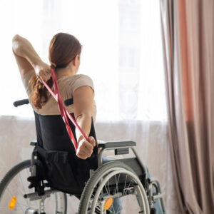 Caucasian woman in a wheelchair doing exercises with the help of fitness rubber bands.