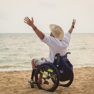 Disabled man in a wheelchair on the beach.