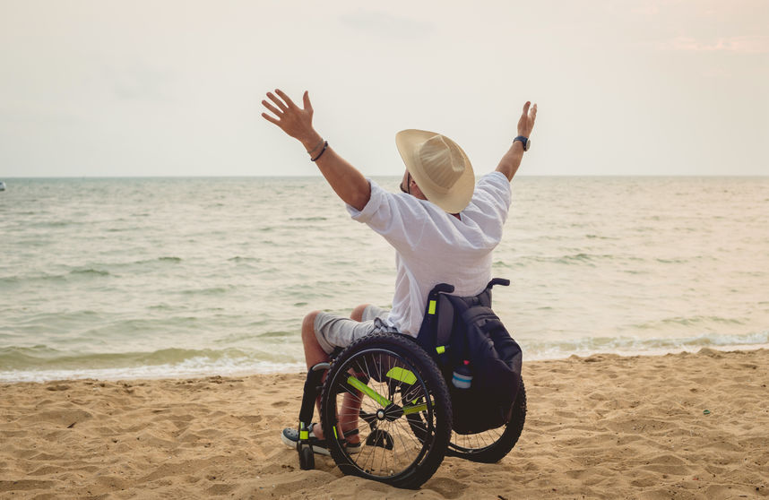 Disabled man in a wheelchair on the beach.