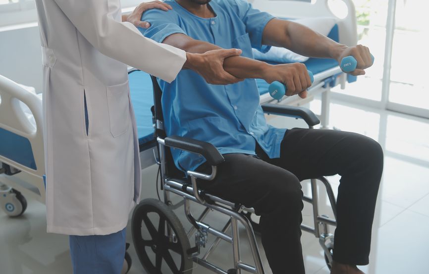 Doctor or physiotherapist working examining treating injured arm of athlete male patient, stretching and exercise, doing the rehabilitation therapy pain in clinic.